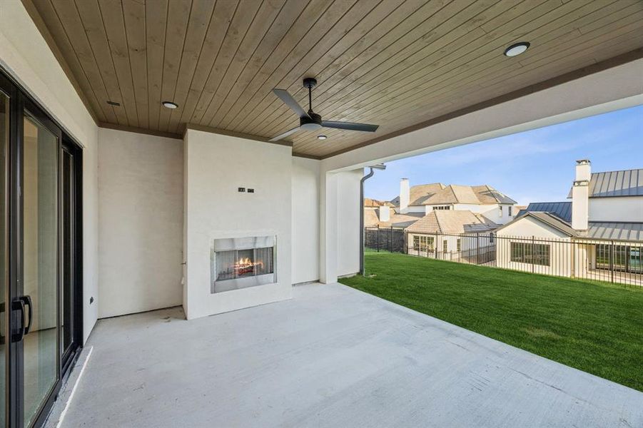 View of patio / terrace featuring a lit fireplace, a ceiling fan, and a residential view View of patio / terrace featuring a lit fireplace, a ceiling fan, and a residential view