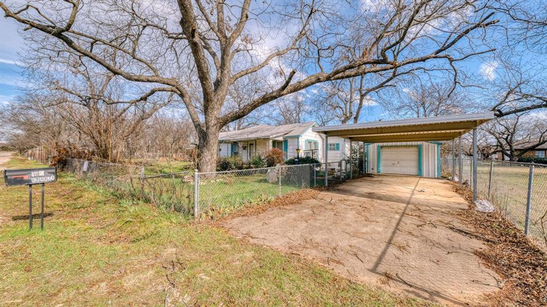 Single story home with a carport, a garage, and an outbuilding