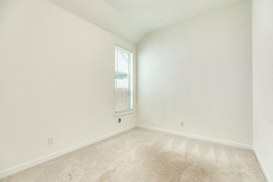 Secondary bedroom located off the kitchen; this spacious room features a peaceful view facing the side of the home.
