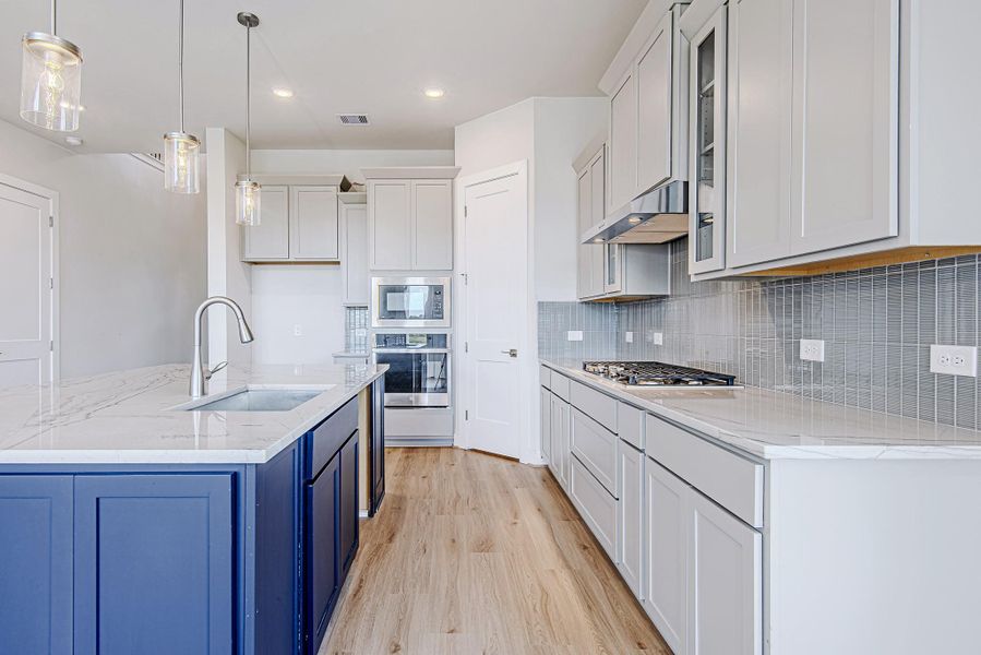 A closer look at the kitchen highlights the sleek gas cooktop, built-in microwave and oven, and soft-close drawers designed for everyday ease. A closer look at the kitchen highlights the sleek gas cooktop, built-in microwave and oven, and soft-close drawers designed for everyday ease.