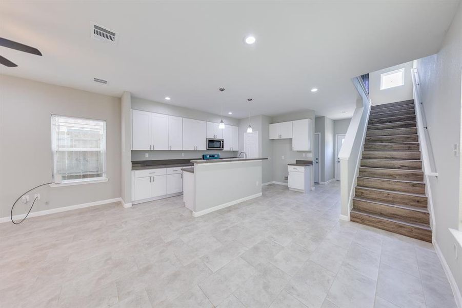 The kitchen is thoughtfully tucked into the corner, maximizing space for hosting and entertaining. Ceiling lights ensure that even the coziest corners are brightly illuminated, creating a warm and inviting atmosphere. Large windows flood the room with natural sunlight, enhancing the bright and open feel, making this kitchen not only functional but also a vibrant and cheerful space perfect for gathering with friends and family.