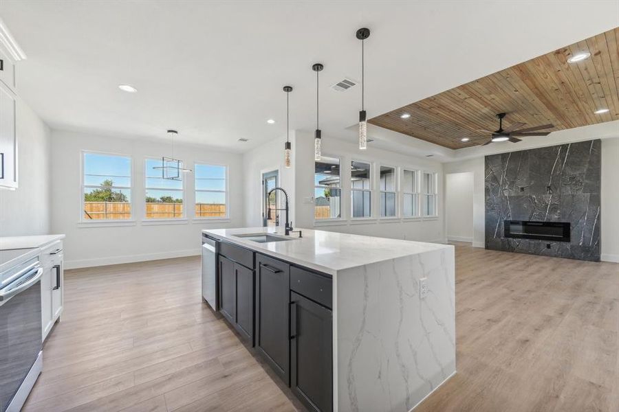 Kitchen with sink, light hardwood / wood-style flooring, an island with sink, decorative light fixtures, and stainless steel appliances