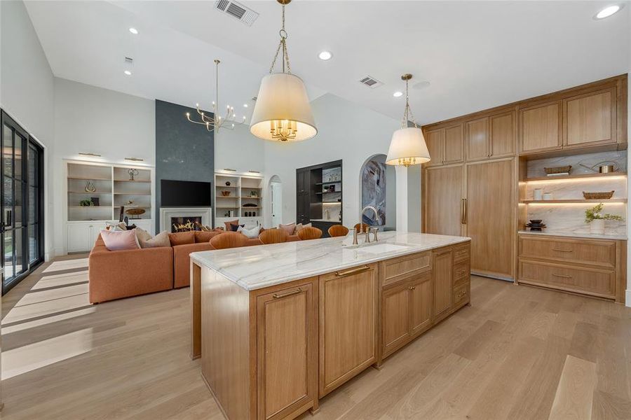 Expansive kitchen island with a stone countertop and integrated sink, complemented by light wood-finish cabinetry