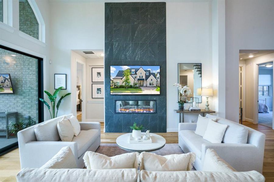 Elevated Everyday Living - Gather in the main living room where a floor-to-ceiling fireplace with sleek tile surround becomes the focal point. Tall ceilings, layered textures, and backyard views create an inspiring space to relax or entertain., a towering ceiling, wood finished floors, and an accent wall Elevated Everyday Living - Gather in the main living room where a floor-to-ceiling fireplace with sleek tile surround becomes the focal point. Tall ceilings, layered textures, and backyard views create an inspiring space to relax or entertain., a towering ceiling, wood finished floors, and an accent wall
