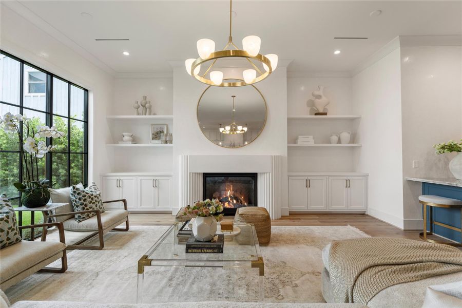 Custom cast stone columns surround the gas log fireplace, perfect for winter ambience. Cabinets are great for blankets, media, and electronics and frame the space nicely. The Carola Ring chandelier gives jus the right balance to the room.
