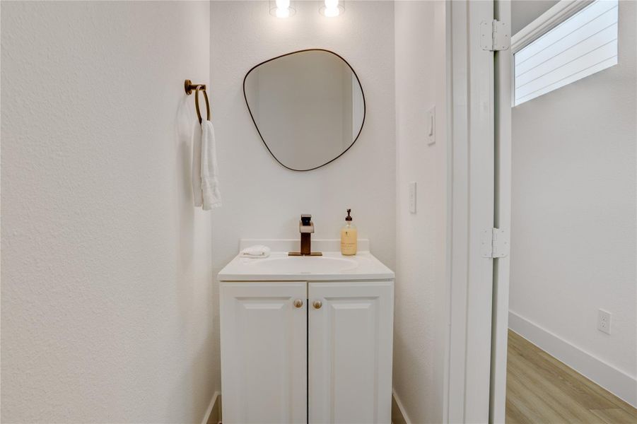 The half-bath is in the entry hallway, away from the living areas, and has contemporary solid-wood cabinets and custom fixtures.