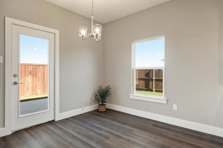 Empty room featuring dark hardwood / wood-style flooring and a notable chandelier Empty room featuring dark hardwood / wood-style flooring and a notable chandelier