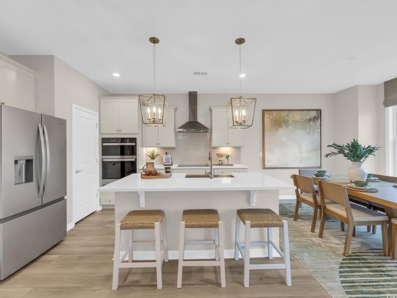 Kitchen featuring appliances with stainless steel finishes, pendant lighting, a breakfast bar area, an island with sink, and decorative backsplash Kitchen featuring appliances with stainless steel finishes, pendant lighting, a breakfast bar area, an island with sink, and decorative backsplash