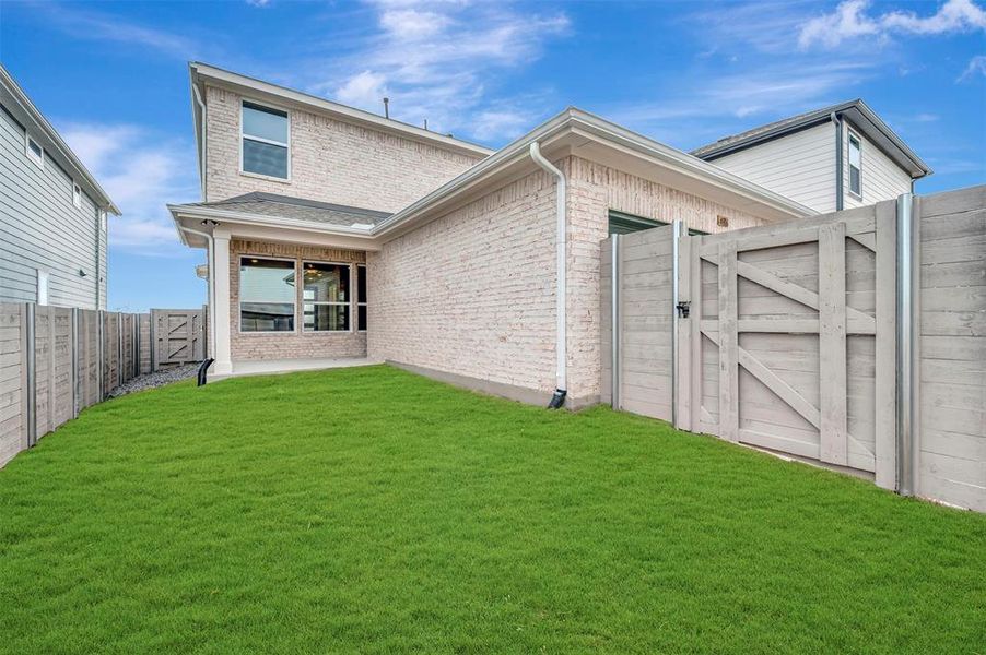 Rear view of property featuring a gate, brick siding, a fenced backyard, and a patio area