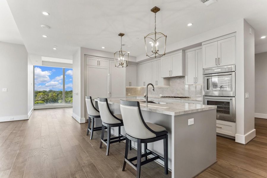 Chef inspired kitchen centers around a large island, illuminated by elegant pendant lights, complete with convenient pull-out seating, making it the perfect spot to sip your morning coffee or enjoy a quick bite.