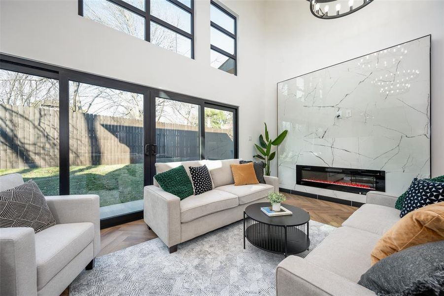 Living area with a chandelier, a towering ceiling, a high end fireplace, and french doors Living area with a chandelier, a towering ceiling, a high end fireplace, and french doors