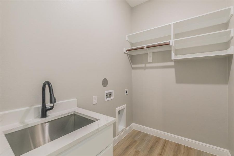 Washroom featuring hookup for an electric dryer, baseboards, washer hookup, and light wood-style flooring Washroom featuring hookup for an electric dryer, baseboards, washer hookup, and light wood-style flooring