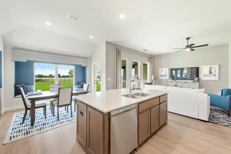 Open-concept kitchen with center island, sink, and views into dining and living areas with hardwood floors