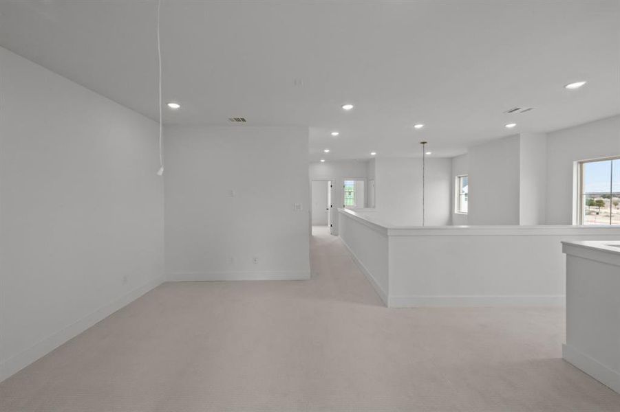 Unfurnished room with light colored carpet and a wealth of natural light