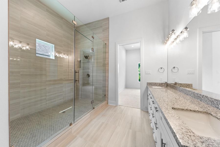 Primary bath boasts an expansive walk-in shower, combining luxury and comfort.