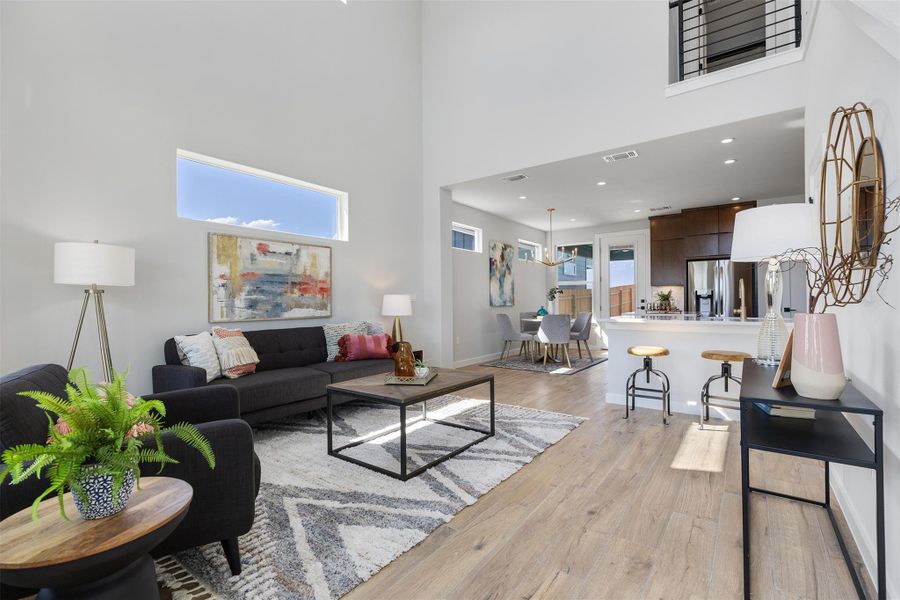 Living room with light wood-type flooring, a towering ceiling, and recessed lighting
