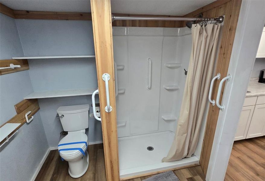 Full bath with a stall shower, wood-type vinyl flooring.