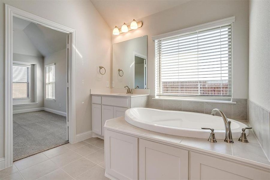 Bathroom with tile patterned flooring, a wealth of natural light, and vaulted ceiling