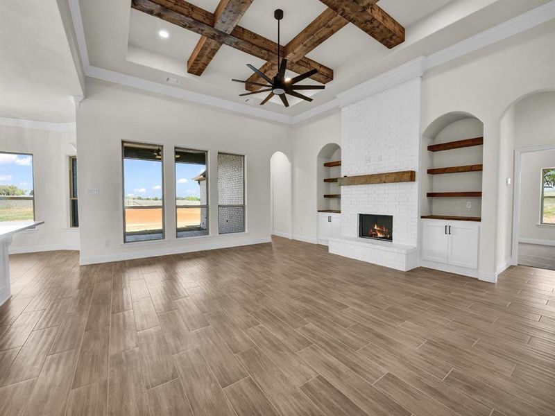 Unfurnished living room with wood tiled floor, a fireplace, arched walkways, and baseboards Unfurnished living room with wood tiled floor, a fireplace, arched walkways, and baseboards