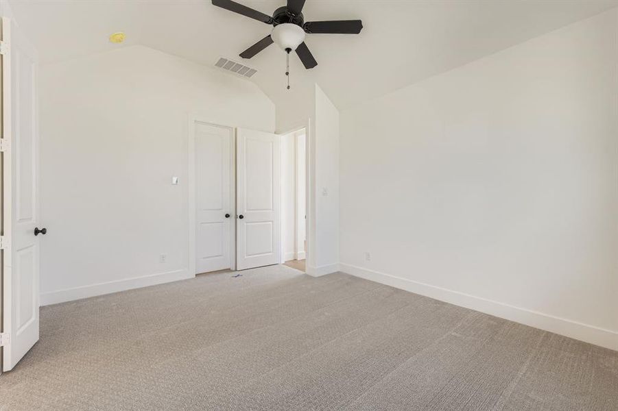 Unfurnished bedroom featuring lofted ceiling, carpet flooring, and a ceiling fan Unfurnished bedroom featuring lofted ceiling, carpet flooring, and a ceiling fan