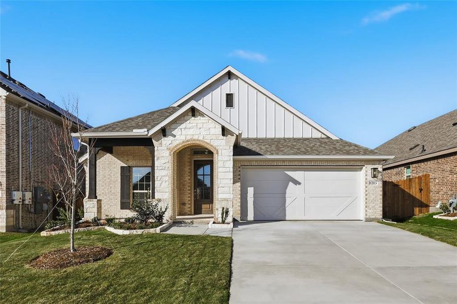 View of front of home with board and batten siding, driveway, brick siding, a garage, and roof with shingles View of front of home with board and batten siding, driveway, brick siding, a garage, and roof with shingles