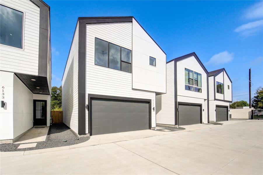 Modern, two-story townhouses with sleek, minimalist design. The homes feature white siding with dark trim, large windows, and two-car garages. With spacious driveway is spacious. Modern, two-story townhouses with sleek, minimalist design. The homes feature white siding with dark trim, large windows, and two-car garages. With spacious driveway is spacious.