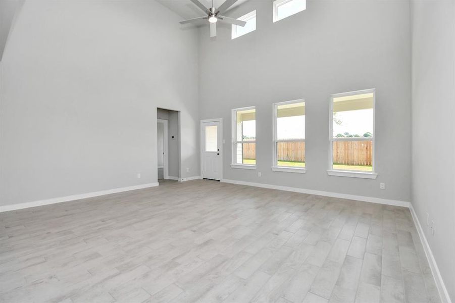 Bring your loved ones and guests together in the inviting living room! Boasting lofty high ceilings, recessed lighting, a stylish ceiling fan, custom paint, stunning flooring, and expansive windows that flood the space with ample natural light all day long. Sample photo of completed home. Actual colors and selections may vary.