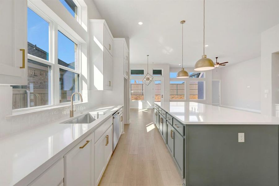 Kitchen featuring two tone cabinets, a large island, pendant lighting, light wood-style flooring, and light stone countertops