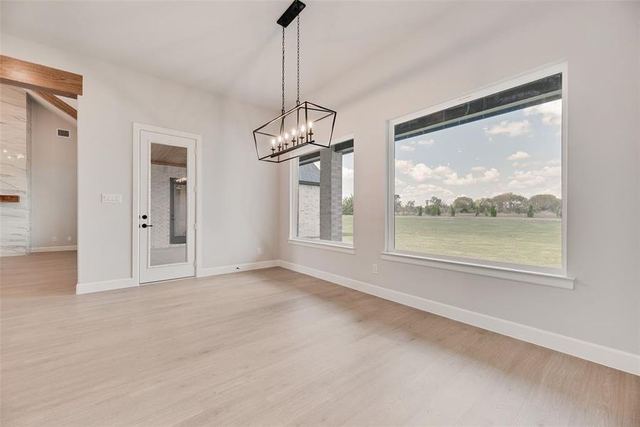 Unfurnished dining area featuring a chandelier and light wood-style flooring