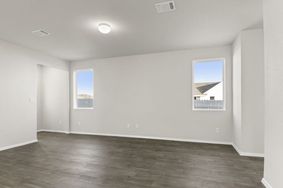 Image of a living room with dark brown wood-like flooring and light grey painted walls with two windows
