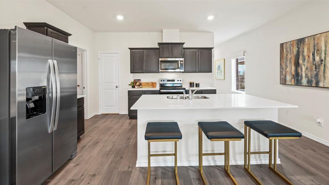 Kitchen featuring stainless steel appliances, a center island with sink, a breakfast bar area, recessed lighting, and dark wood-type flooring