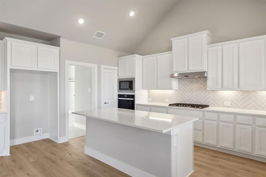 Kitchen featuring a center island, white cabinetry, black oven, and tasteful backsplash