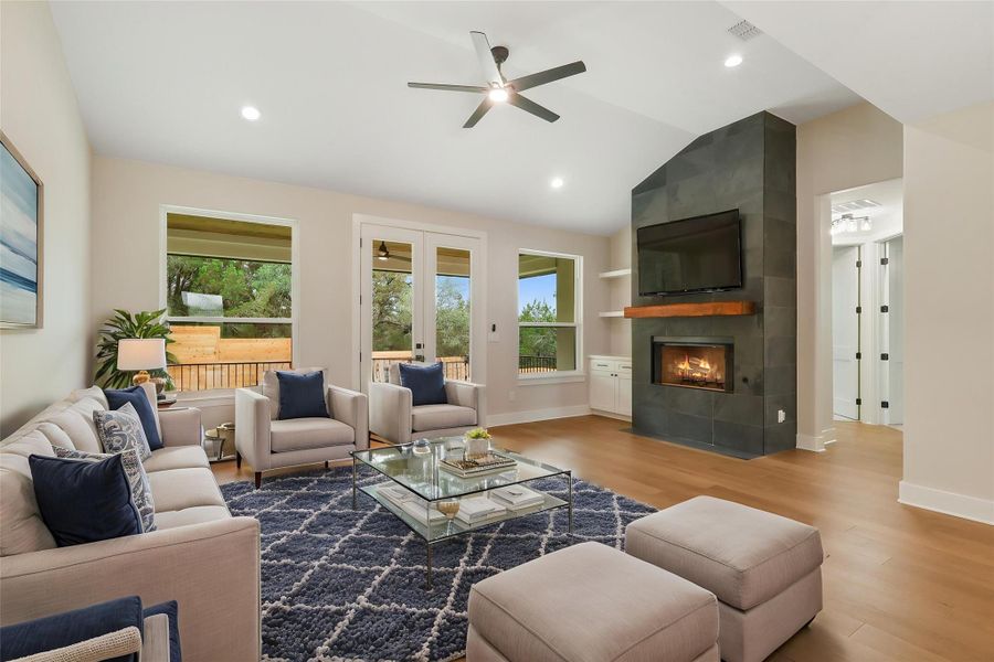 Living room featuring lofted ceiling, a wealth of natural light, wood finished floors, and baseboards Living room featuring lofted ceiling, a wealth of natural light, wood finished floors, and baseboards