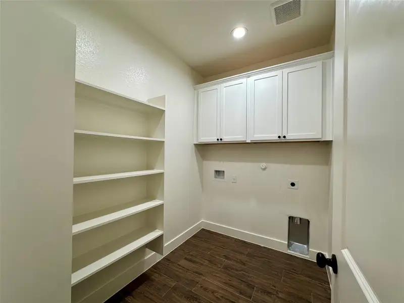Washroom featuring electric dryer hookup, dark wood-type flooring, gas dryer hookup, hookup for a washing machine, and cabinet space