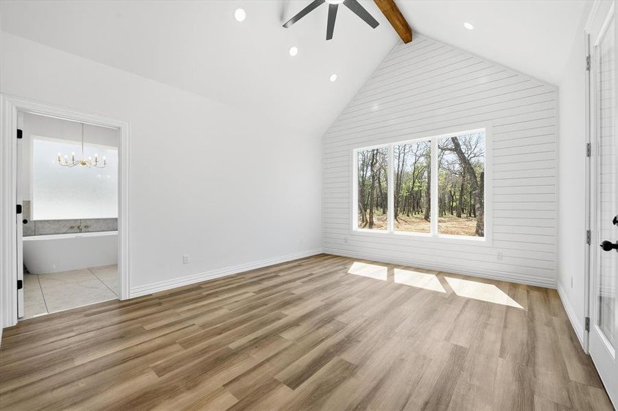 Unfurnished bedroom with light wood finished floors, a ceiling fan, suspended lighting, and ensuite bathroom