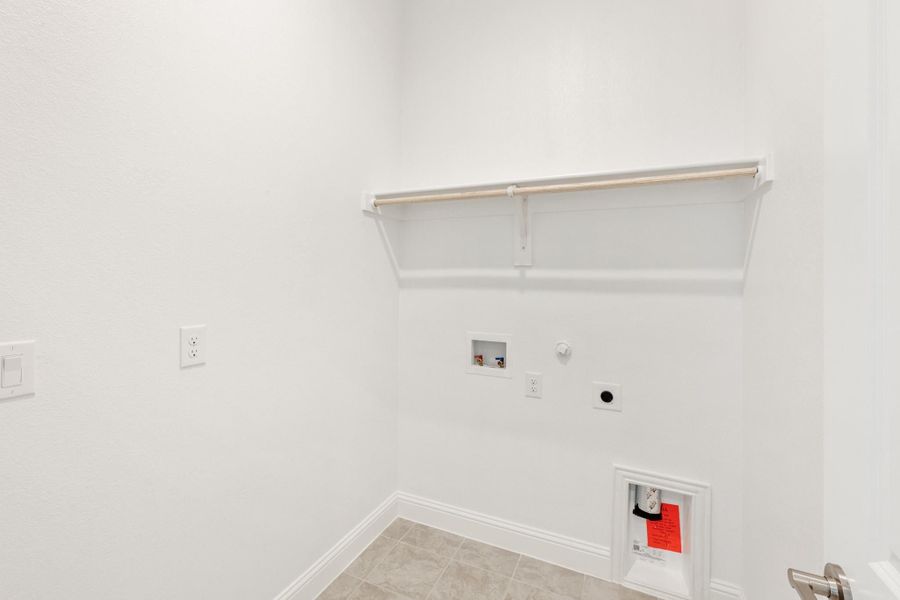 Laundry room with wall-mounted shelf, washer hookups, and tile floor