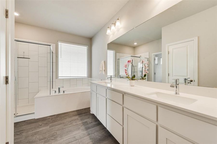 Full bathroom featuring a garden tub, a stall shower, double vanity, dark wood-style floors, and recessed lighting