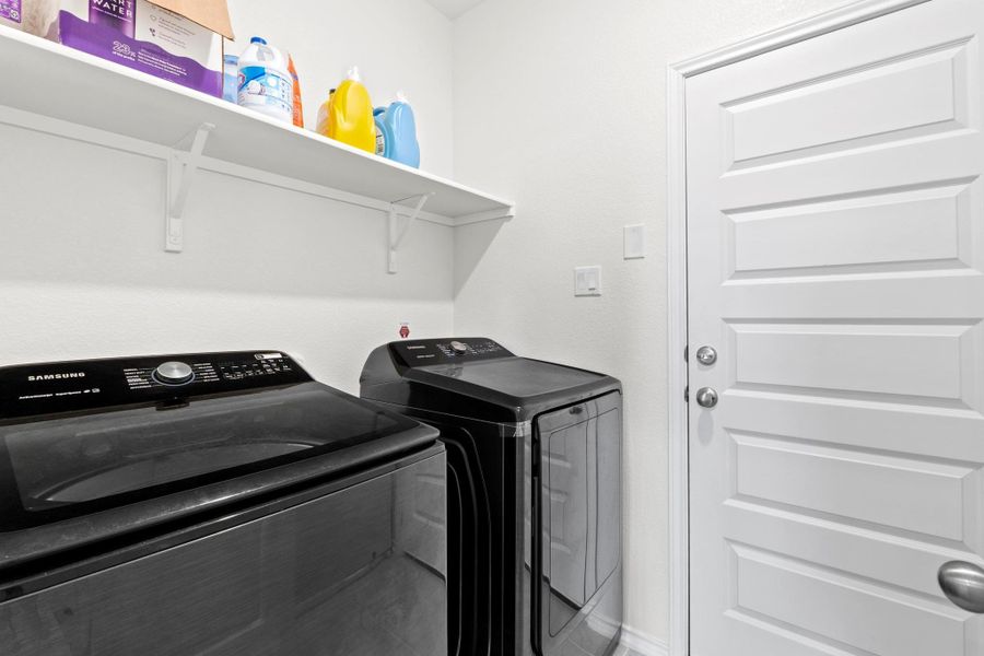 Dedicated laundry space featuring a white wall shelf, textured white walls, and a paneled interior door