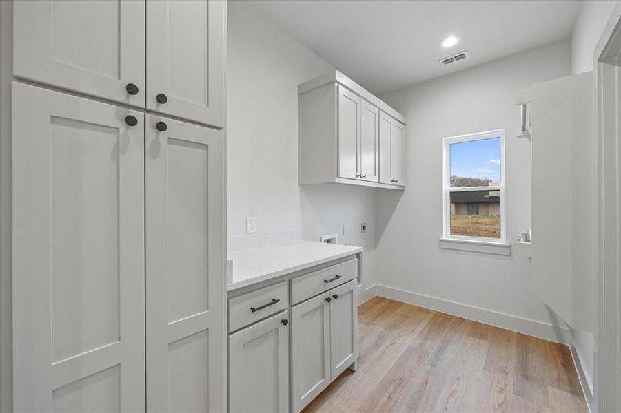 Clothes washing area featuring cabinets, washer hookup, hookup for an electric dryer, and light hardwood / wood-style floors