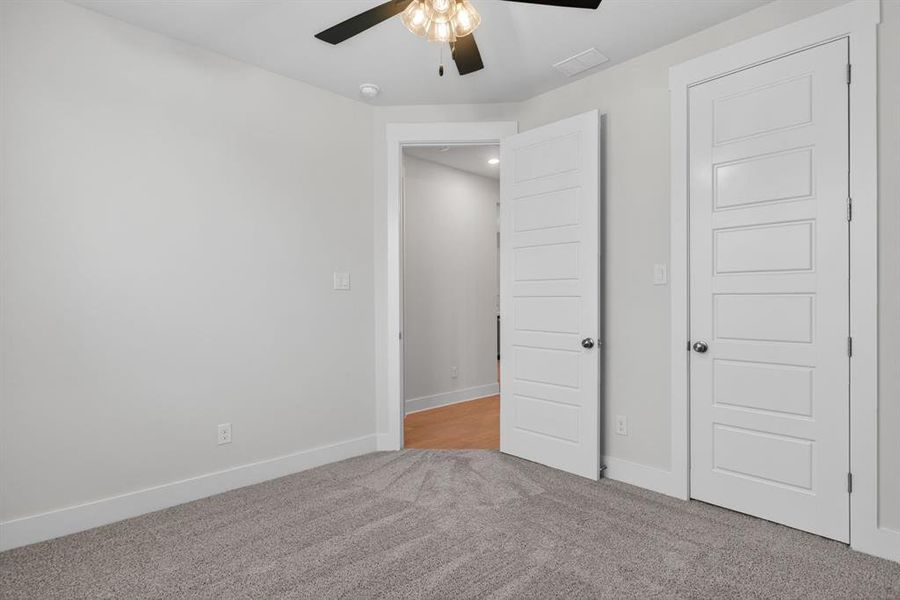 Neutral tone walls with white trim, gray textured carpeting, and a ceiling fan with integrated lighting Neutral tone walls with white trim, gray textured carpeting, and a ceiling fan with integrated lighting