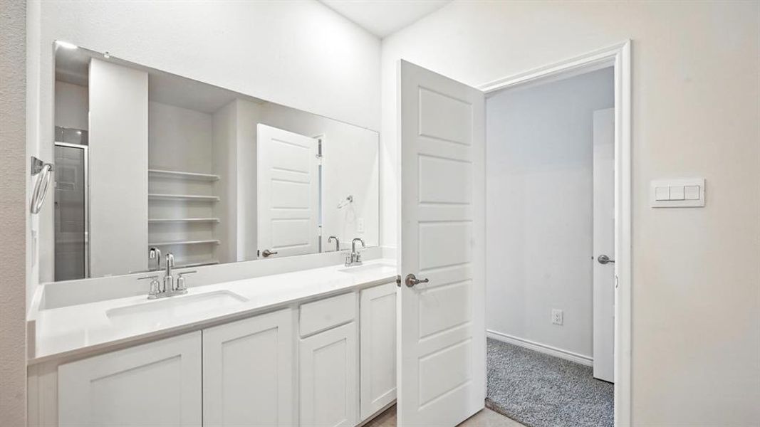 Bathroom with a shower stall, double vanity, and light colored carpet