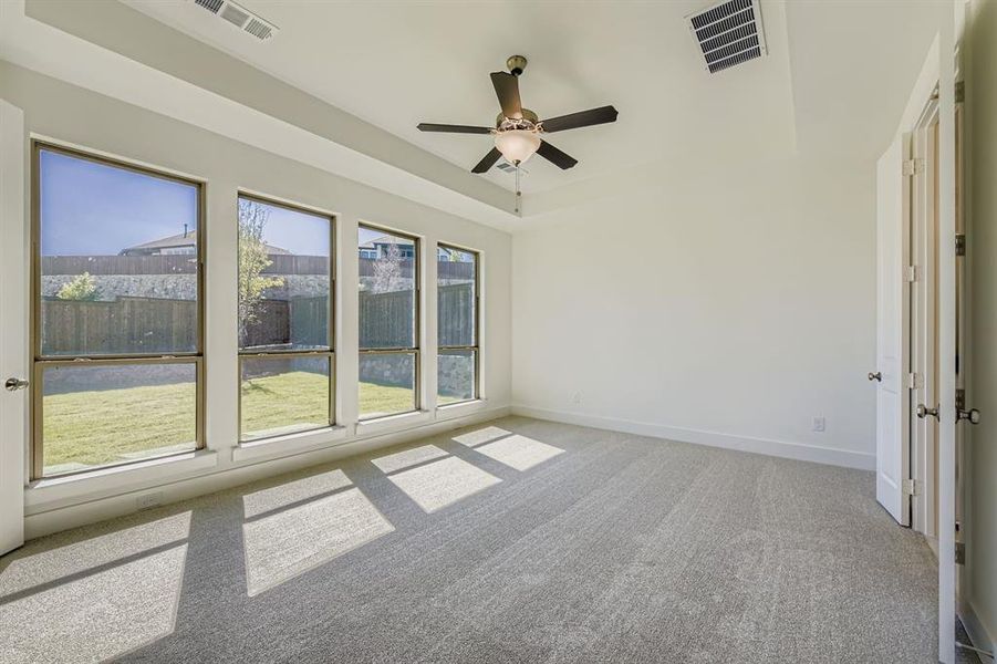 Spare room featuring a tray ceiling, light colored carpet, and ceiling fan Spare room featuring a tray ceiling, light colored carpet, and ceiling fan