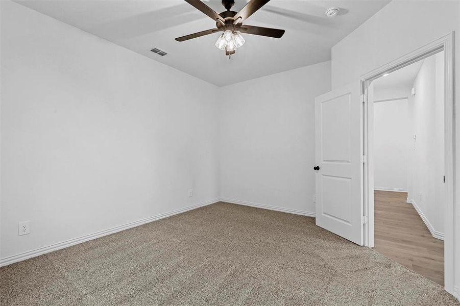 Empty room with light colored carpet and ceiling fan