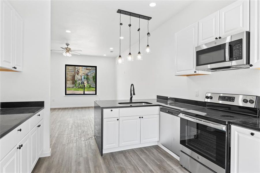 Kitchen featuring white cabinetry, kitchen peninsula, appliances with stainless steel finishes, and sink