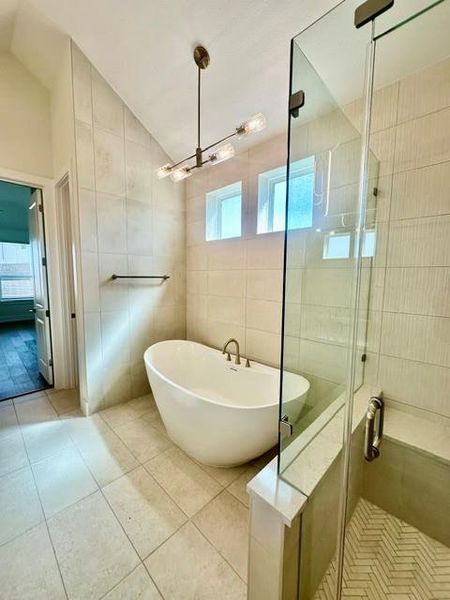 A well-appointed primary bathroom showcases a freestanding soaking tub and a spacious glass-enclosed shower.
