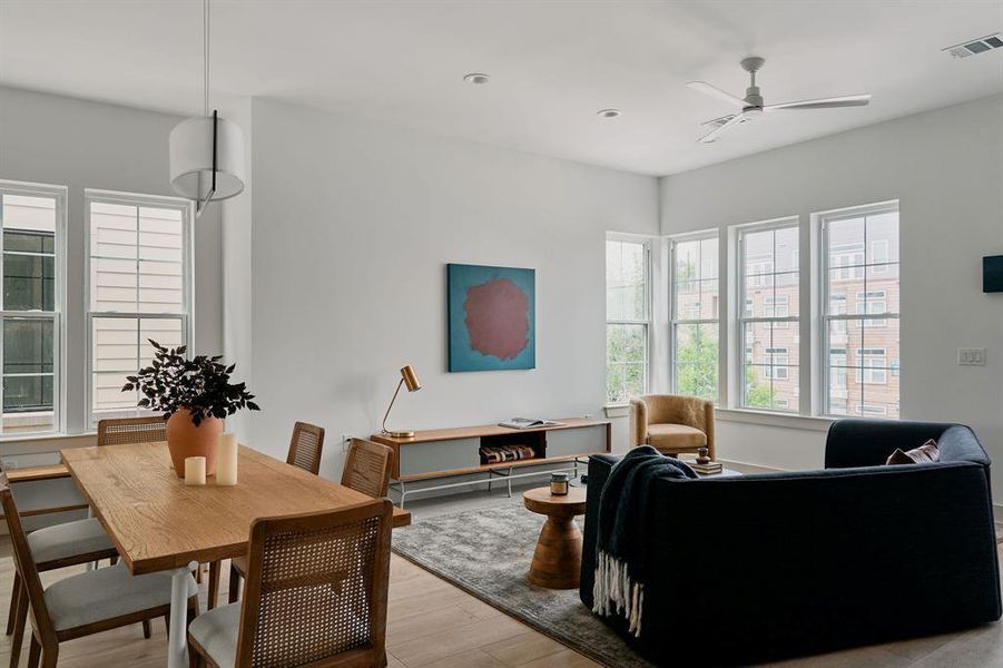 Bright living area featuring wood-finish flooring, ample natural light from multiple windows, recessed lighting, and a ceiling fan Bright living area featuring wood-finish flooring, ample natural light from multiple windows, recessed lighting, and a ceiling fan