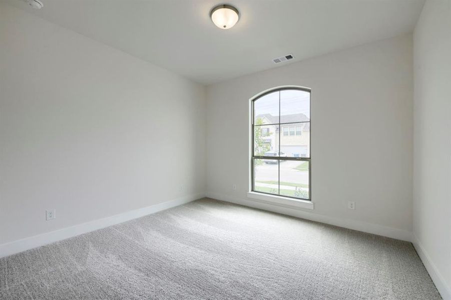 Room featuring an arched window, light gray carpet, white baseboards, and a flush-mount ceiling light Room featuring an arched window, light gray carpet, white baseboards, and a flush-mount ceiling light