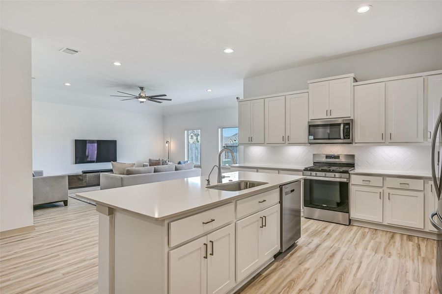 The oversized island anchors the kitchen with generous workspace, an undermount sink, dishwasher and additional cabinetry, while the open design keeps the cook connected to the adjoining family room. The oversized island anchors the kitchen with generous workspace, an undermount sink, dishwasher and additional cabinetry, while the open design keeps the cook connected to the adjoining family room.
