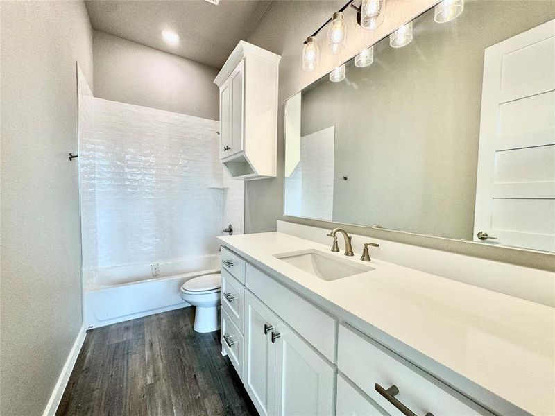 Full bathroom with toilet, hardwood / wood-style flooring, shower / washtub combination, and vanity