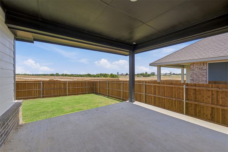 Covered concrete patio with a dark ceiling and recessed lighting, featuring a private fenced yard with a grass lawn Covered concrete patio with a dark ceiling and recessed lighting, featuring a private fenced yard with a grass lawn